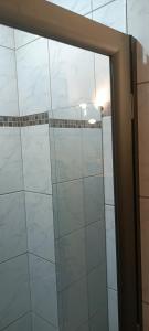 uma porta de duche em vidro numa casa de banho com azulejos brancos em Chez Audray em Saint-Pardoux-Isaac
