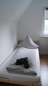 ein weißes Bett mit einem Kissen auf dem Zimmer in der Unterkunft Ferienwohnung Siegen in Siegen