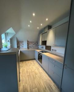 a kitchen with white cabinets and a wooden floor at Spacious Apartment NEC BHX in Solihull