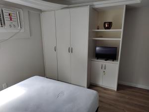 a white bedroom with a bed and a tv at BOA VIAGEM FLATS APTO 201 in Recife