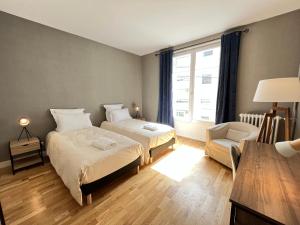 a bedroom with two beds and a chair and a window at La Villa Maignan - Centre ville - Jardin - 15p in Le Mans