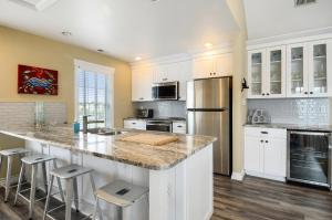 a kitchen with white cabinets and a large island with bar stools at 1606 - Shades of Sand in Corolla