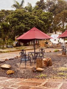 - une table de pique-nique avec un parasol et des chaises rouges dans l'établissement Hostal Casa Ceiba, à Barichara