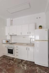 cocina con armarios blancos y nevera blanca en Apartamento DREAM BAENA en Baena