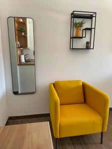 una silla amarilla en una habitación con espejo en Apartman 'Tramonto' Srebrno Jezero, en Veliko Gradiste