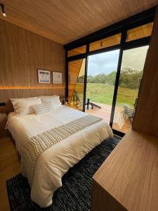 a bedroom with a large bed and a large window at Valle Fiori in Balsa Nova