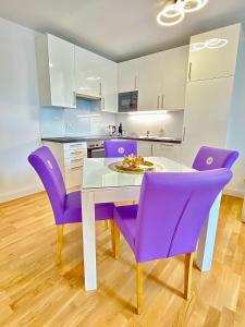 a kitchen with a white table and purple chairs at Steiner Residences Vienna Nestroyplatz in Vienna