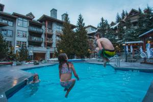 a group of people jumping into a swimming pool at Blackcomb Springs Suites by CLIQUE in Whistler
