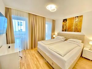 a bedroom with a large white bed and a window at Steiner Residences Vienna Nestroyplatz in Vienna