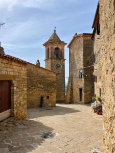 a large stone building with a clock tower at La Petite Fenêtre in Casale Marittimo