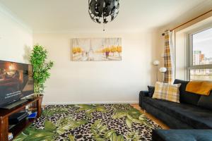 uma sala de estar com um sofá e uma janela em Luxury Riverview 2Bed Apt- 5 mins from Excel London, Canary wharf, 02 Arena - Free Parking - PlayStation 4 Provided em Londres