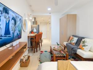 een woonkamer met een bank en een tv bij New Cozy Studio in Commonwealth Batasan, Katipunan in Manilla