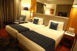 a hotel room with two beds and a chair at The Place Gurugram, a member of Radisson Individuals in Gurgaon