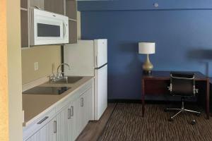 a kitchen with a sink and a desk with a microwave at Suburban Studios Arlington Heights Elk Grove in Arlington Heights