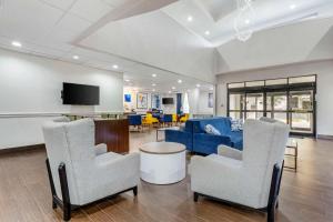 sala de estar con sofá azul y sillas en Comfort Suites Houston NW - Vintage Park, en Houston