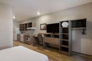 a bedroom with a desk with a tv and a bed at WoodSpring Suites Olympia - Lacey in Olympia