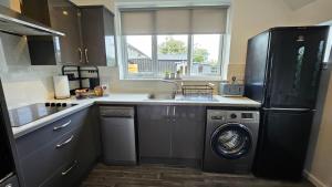 a kitchen with a refrigerator and a washing machine at Contemporary Highland Cottage in Invergordon