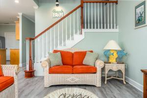 - un canapé orange dans un salon avec des escaliers dans l'établissement Southern Dunes West - 332 Audubon Pl Unit A home, à Dauphin Island