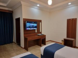 um quarto de hotel com uma cama e uma televisão em الديار الفاخرة للشقق المخدومة em Al Qunfudhah