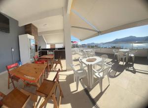 a patio with tables and chairs and an umbrella at Suítes com Vista para o Mar no Marinas - Mirante do Marinas in Angra dos Reis