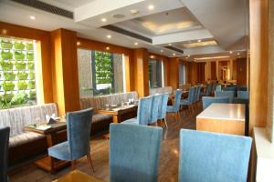 a restaurant with blue chairs and tables and windows at The Place Gurugram, a member of Radisson Individuals in Gurgaon