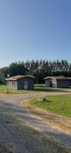 un camino de grava con dos edificios pequeños en un campo en Lundby Camping, en Nibe