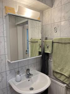 ein Badezimmer mit einem Waschbecken, einem Spiegel und Handtüchern in der Unterkunft Modernes Appartement Sauerland in Hachen