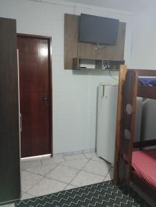 um quarto com uma cozinha com um frigorífico e uma porta em Hostel do Enzo em Itanhaém