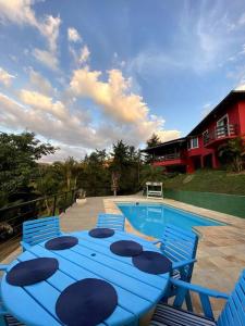 a blue table and chairs next to a swimming pool at Casa em Secretário (@chacaradosolsecretario) in Petrópolis