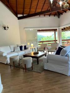 a living room with white couches and a table at Casa em Secretário a 800 metros do centro de Secretário chacaradosolsecretario in Petrópolis