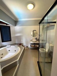 a bathroom with a tub and a sink and a toilet at Casa em Secretário (@chacaradosolsecretario) in Petrópolis