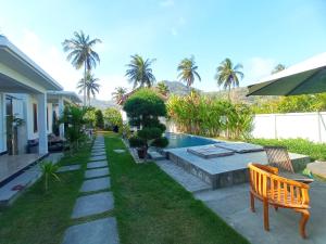 a backyard with a pool and a bench and palm trees at torok ocean homestay in Mataram