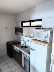 a small kitchen with a sink and a microwave at Apartamento Praia de Ponta Verde com um quarto in Maceió