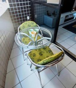 a glass table with two chairs and a glass table with a banana at Apartamento Praia de Ponta Verde com um quarto in Maceió