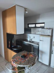 a kitchen with a table and a white refrigerator at Apartamento Praia de Ponta Verde com um quarto in Maceió
