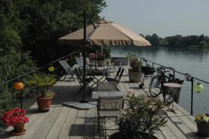 a wooden deck with tables and chairs and an umbrella at Péniche Espoir in Avignon