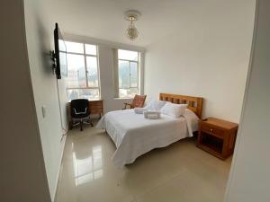 um quarto com uma cama, uma cadeira e uma janela em (1902A) - Apto en el Corazón de la Ciudad con Vista Única em Bogotá