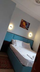 1 dormitorio con 1 cama con cabecero azul en La Cité des Anges, en Nkongsamba