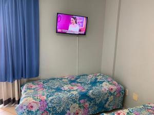 a bedroom with a bed and a tv on the wall at Thermas Place- Caldas Novas(512) in Caldas Novas