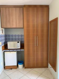 a kitchen with wooden cabinets and a microwave at Thermas Place- Caldas Novas(512) in Caldas Novas