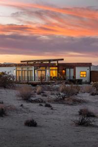 un edificio en el desierto con una puesta de sol en el fondo en Panoramic Heaven - Luxury Designer Property w Spa, en Joshua Tree