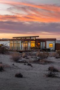 a building in the desert with a sunset in the background at Panoramic Heaven - Luxury Designer Property w Spa in Joshua Tree