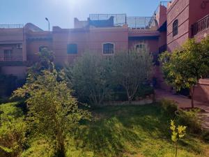 un bâtiment avec une cour arborée devant elle dans l'établissement Duplex Elias, à Marrakech