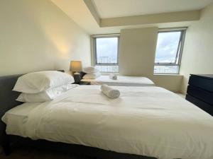 two beds in a bedroom with two windows at North Sydney 2 Bedroom - Pool Parking Gym Spa Sleeps 6 in Sydney