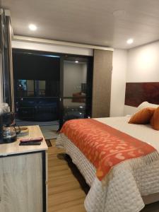 1 dormitorio con 1 cama y escritorio con mando a distancia en Villa Dante, en Firavitoba