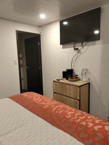 1 dormitorio con 1 cama y TV de pantalla plana en Villa Dante, en Firavitoba
