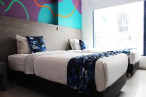 a bedroom with two beds and a colorful wall at Agora Suites Self-Service Boutique Hotel in Bogotá