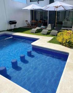 una piscina con sillas y sombrillas junto a una casa en Casa More con alberca, jacuzzi, climatizada, en Tequesquitengo
