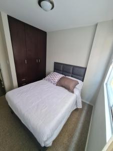 1 dormitorio con 1 cama grande con sábanas blancas en Acogedor Departamento centrico en Cochabamba