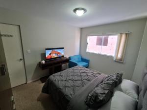 1 dormitorio con 1 cama, TV y ventana en Acogedor Departamento centrico en Cochabamba